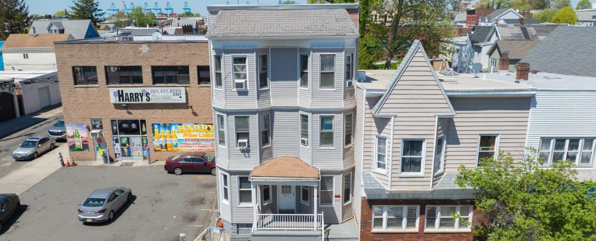 Three-story gray-sided Bayonne multifamily property at 301 Broadway with a covered front porch